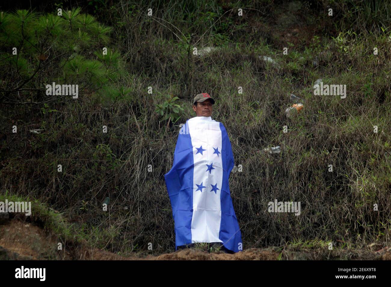 A supporter of Honduras' ousted president Manuel Zelaya wraps himself with a Honduras flag during a protest on the outskirts of Tegucigalpa July 17, 2009. Venezuelan President Hugo Chavez said on Friday ousted Honduran President Manuel Zelaya would return to his country "in the coming hours," casting doubt on the outcome of mediation talks set for Saturday. REUTERS/Edgard Garrido (HONDURAS POLITICS) Stock Photo