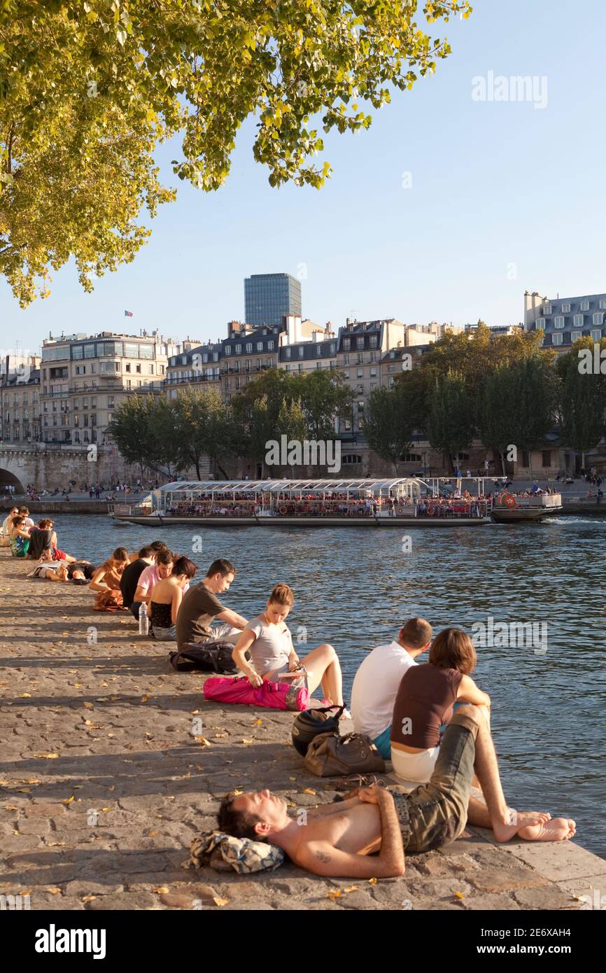 People sitting on the Seine at the Quai de Orleans. Stock Photo