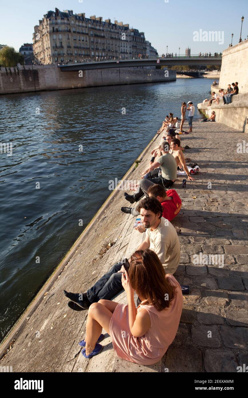 People sitting on the Seine at the Quai de Orleans. Stock Photo