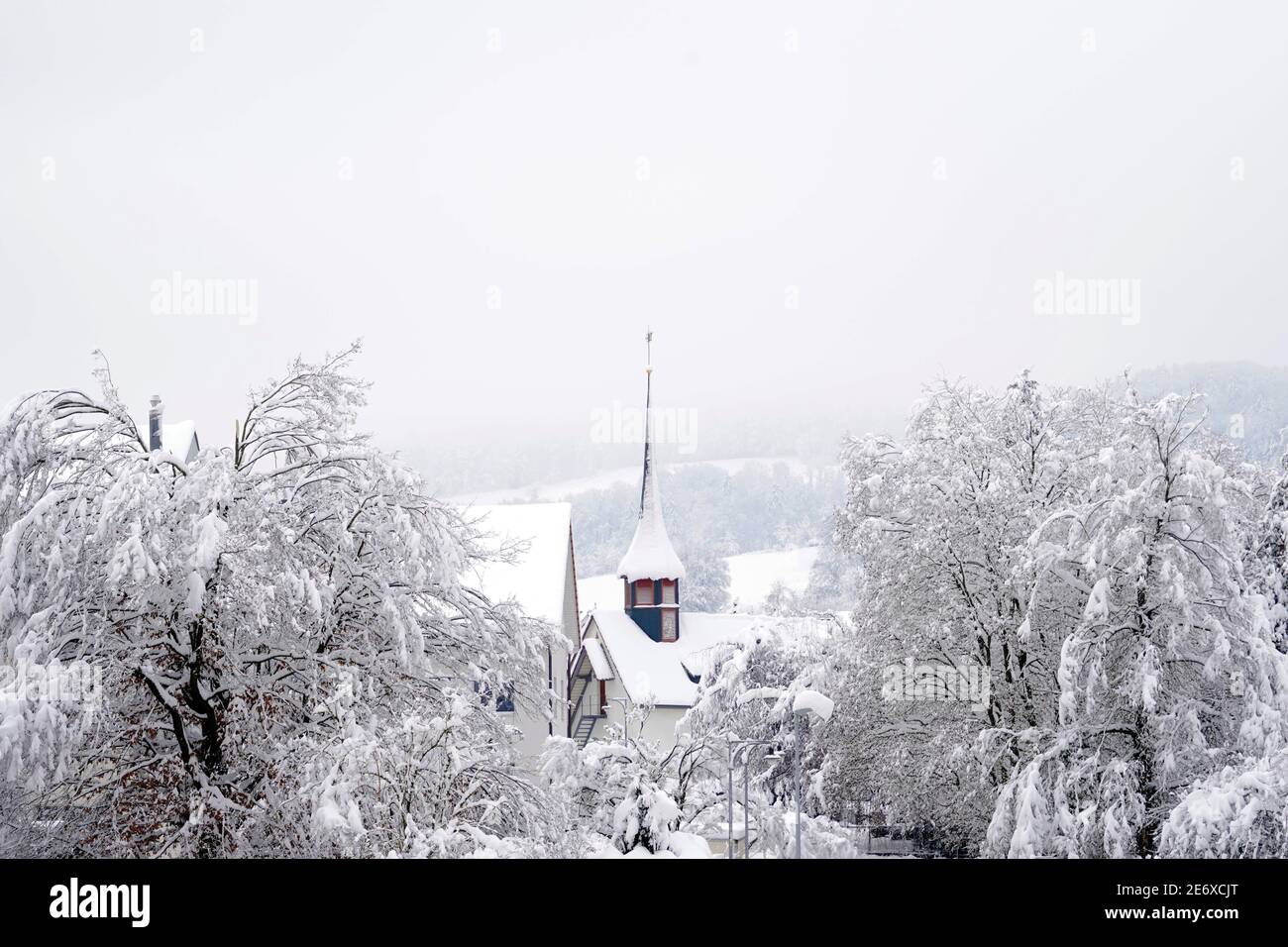 Old reformed church building in Urdorf, Switzerland in winter surrounded with trees, everything covered with snow after extreme snowfall, January 2021 Stock Photo