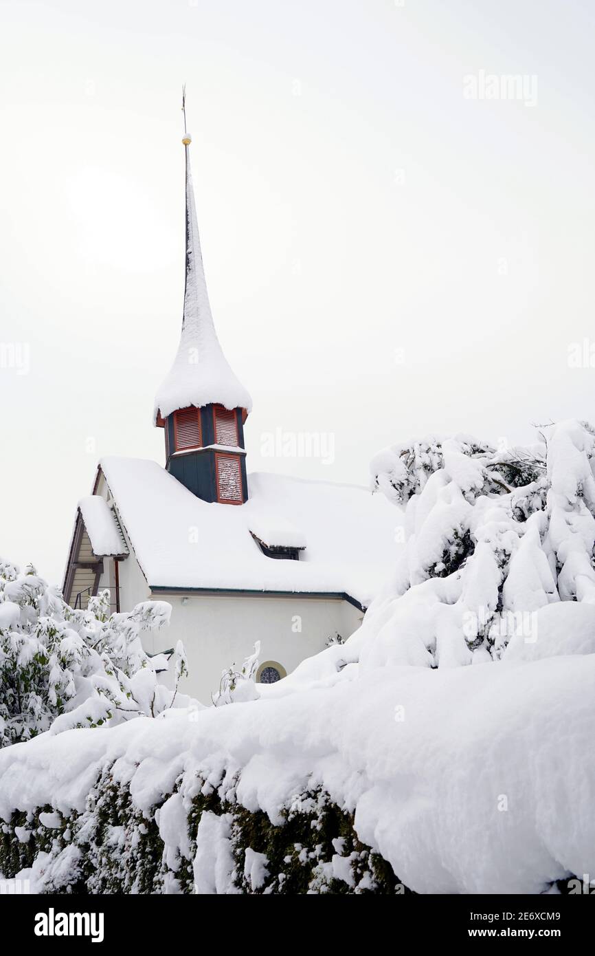 Urdorf, Switzerland - 01 16 2021: Old reformed church in Urdorf, Switzerland in winter close up in low angle view, everything covered with snow. Stock Photo