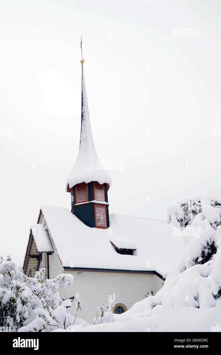 Old reformed church building in Urdorf, Switzerland in winter close up, the rooftop and the surroundings covered with snow after extreme snowfall. Stock Photo