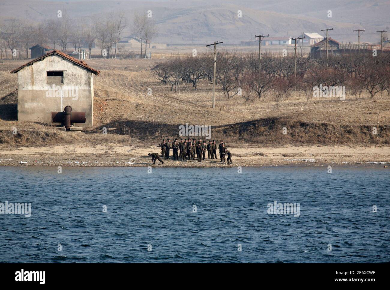 North Korean soldiers play with stones while guarding the banks of Yalu River near the North Korean town of Sinuiju, opposite the Chinese border city of Dandong, March 10, 2010. China has acquired a 10-year lease of Rajin port on North Korea's east coast, potentially increasing shipping access to the Sea of Japan, a provincial official said during China's annual legislative meeting. REUTERS/Jacky Chen (NORTH KOREA - Tags: MILITARY BUSINESS POLITICS) Stock Photo