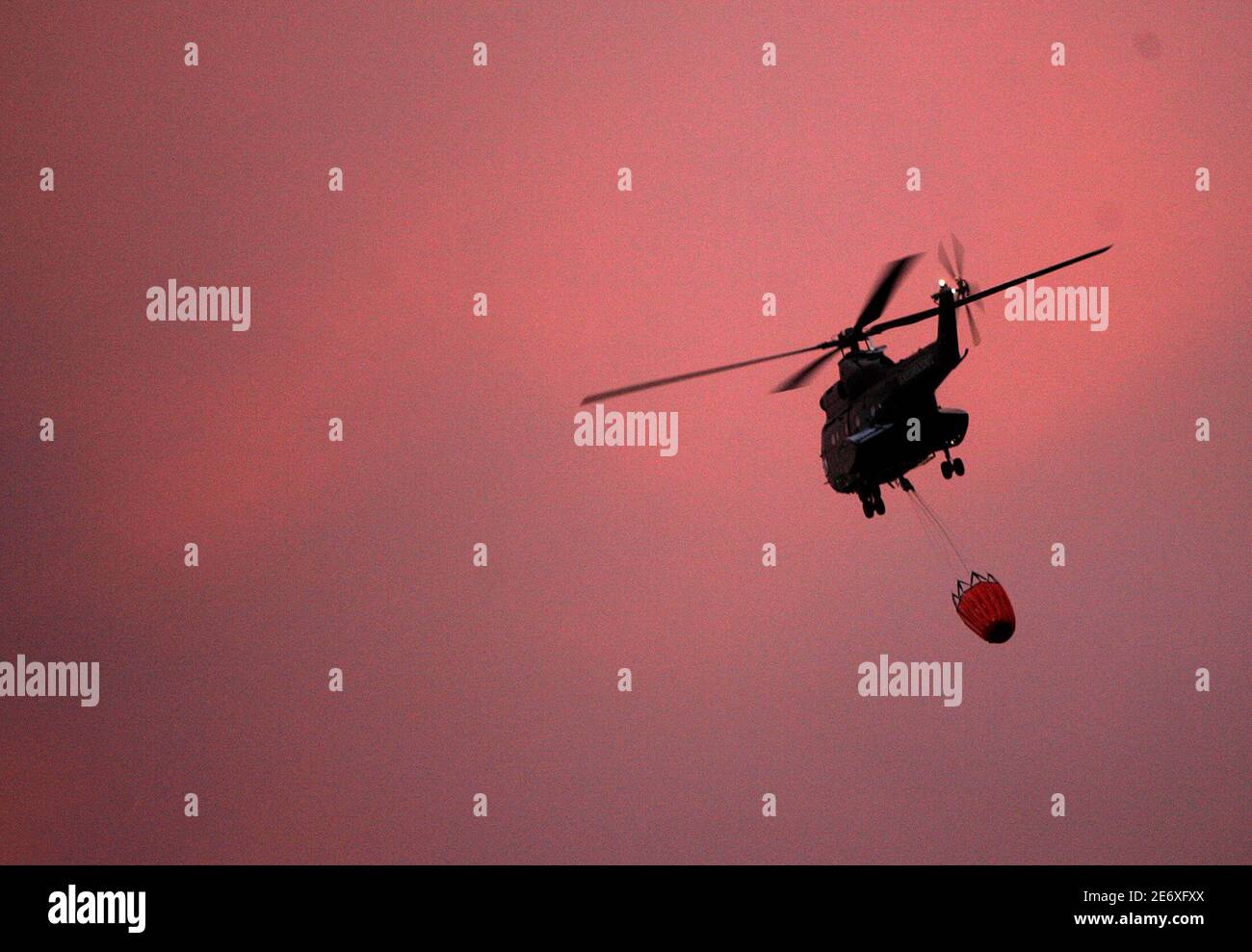 A German Puma helicopter carries water in a bucket during a forest fire in  Miranda Do Corvo, near Coimbra in central Portugal August 23, 2005.  Water-dumping aircraft from around Europe battled on