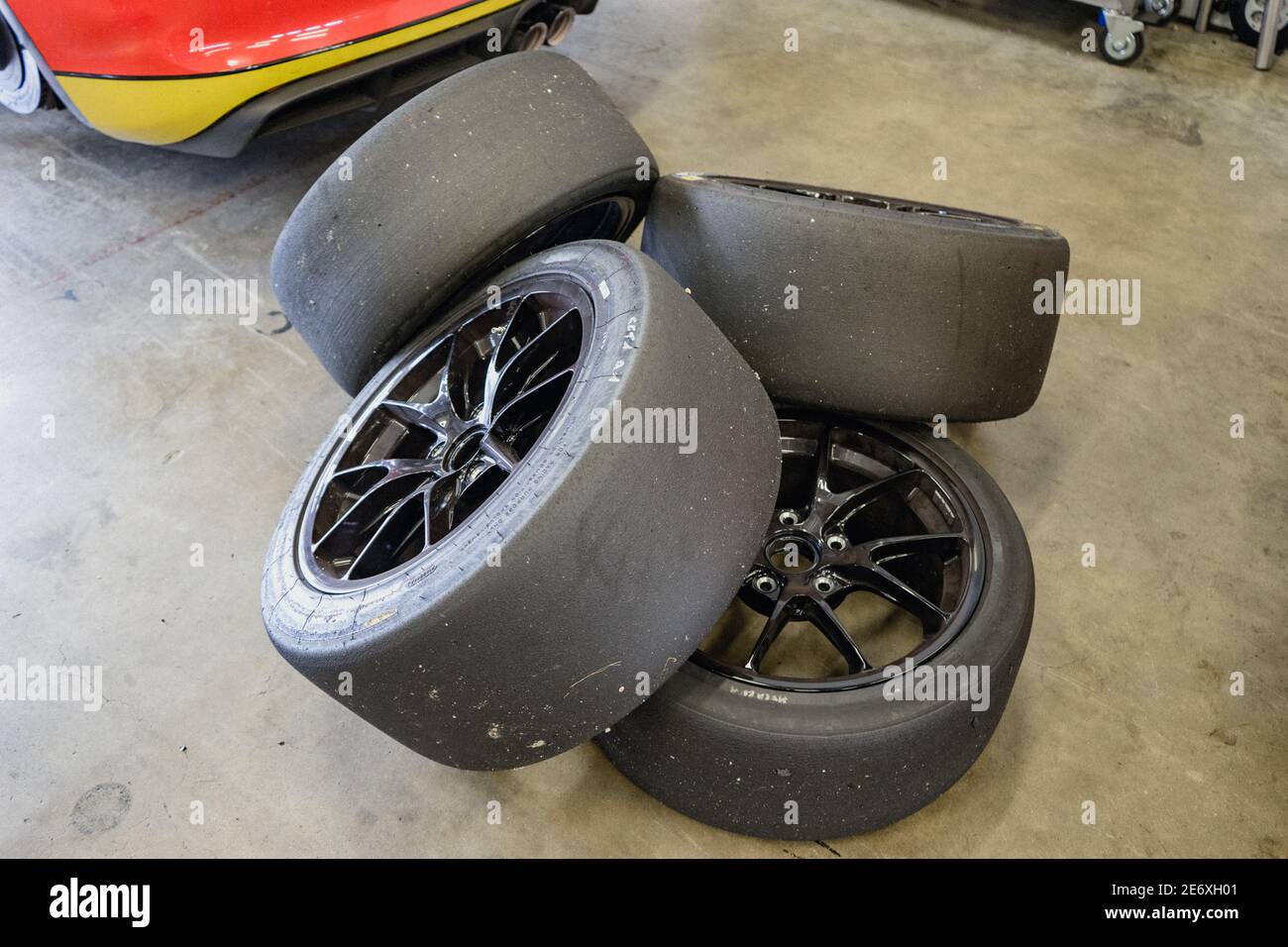 Four slick racing tires behind a race car. Stock Photo