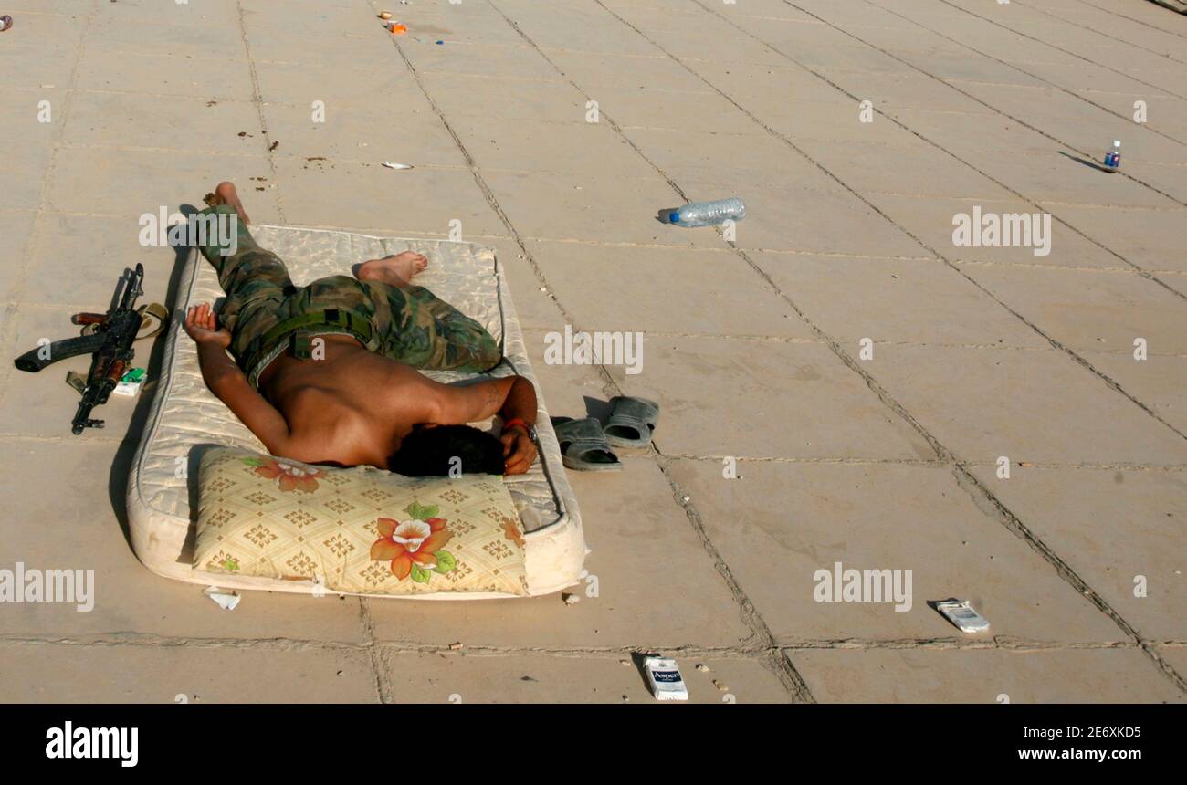 An Iraqi soldier sleeps next to his Kalashnikov rifle on the roof of a base in Baquba June 29, 2007.  REUTERS/Goran Tomasevic    (IRAQ) Stock Photo
