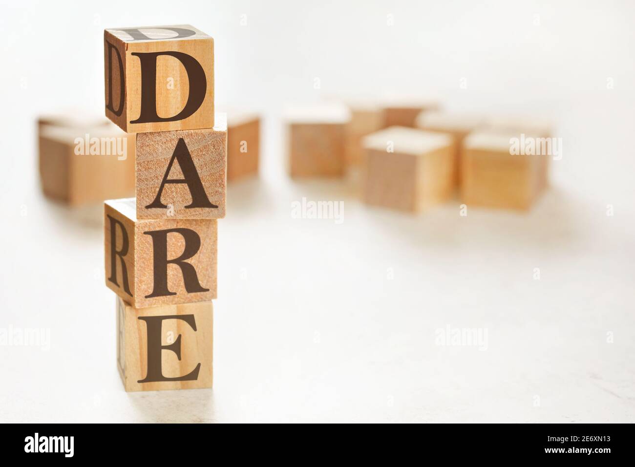 Four wooden cubes arranged in stack with text DARE (meaning Define, Assess, Respond, Evaluate) on them, space for text / image at down right corner Stock Photo