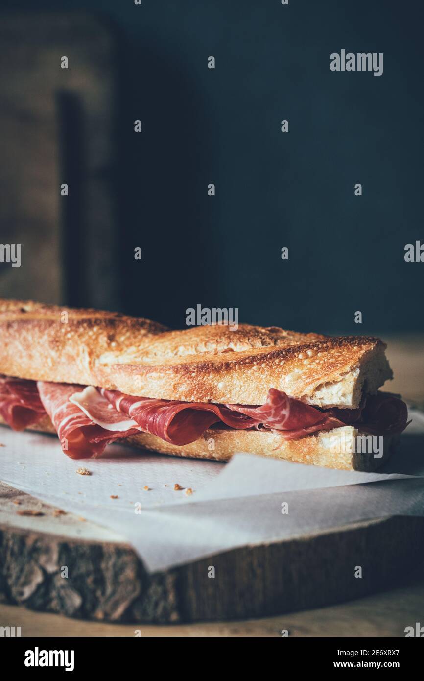 Vertical shot of a bread baguette filled with jamón ibérico or iberian ham Stock Photo