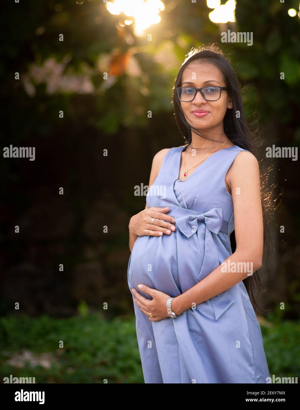 Young adorable looking pregnant lady holding belly with both hands