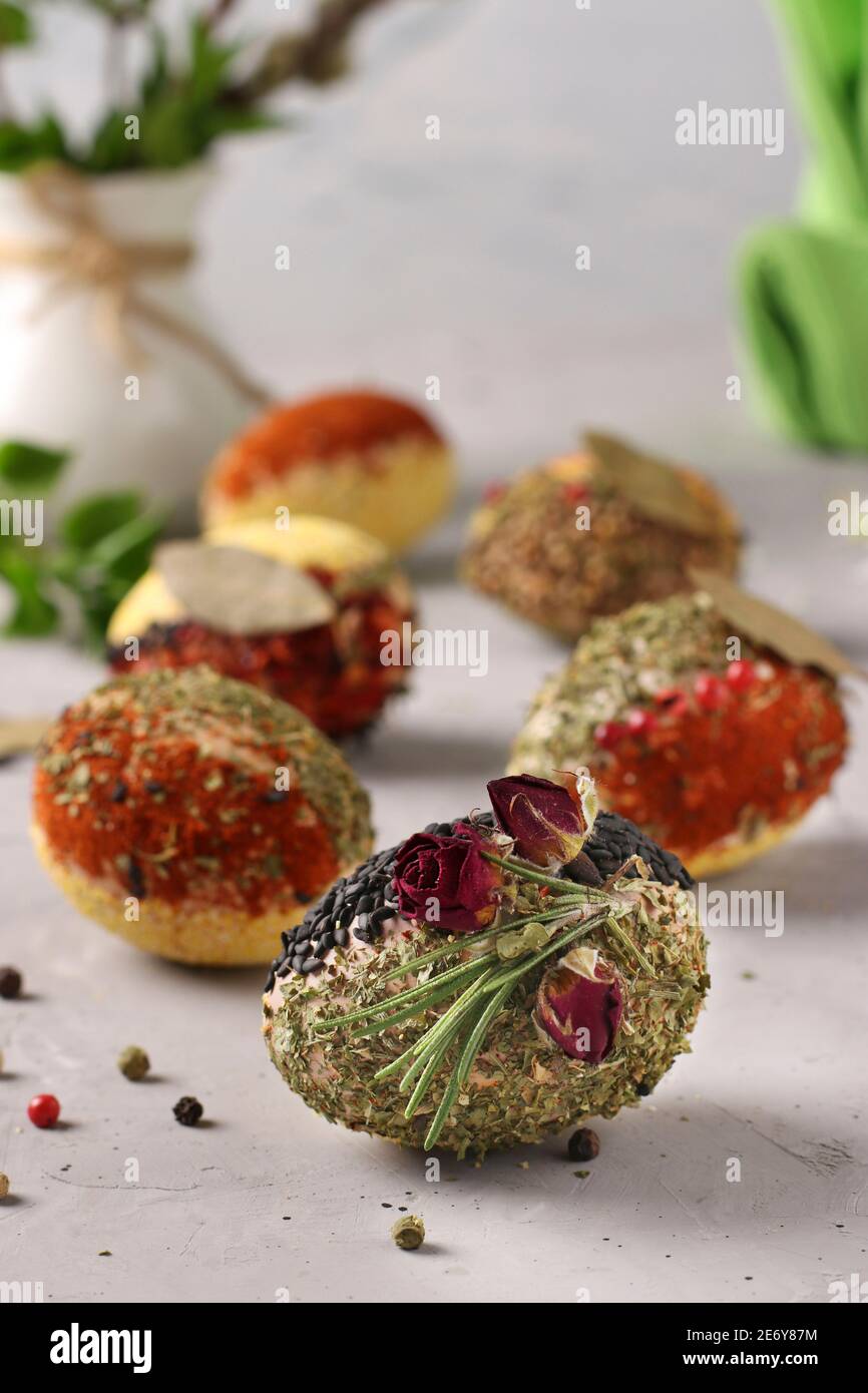 Eco-design of Easter eggs with various spices and cereals, without dyes and preservatives on a gray concrete background. Vertical format. Stock Photo