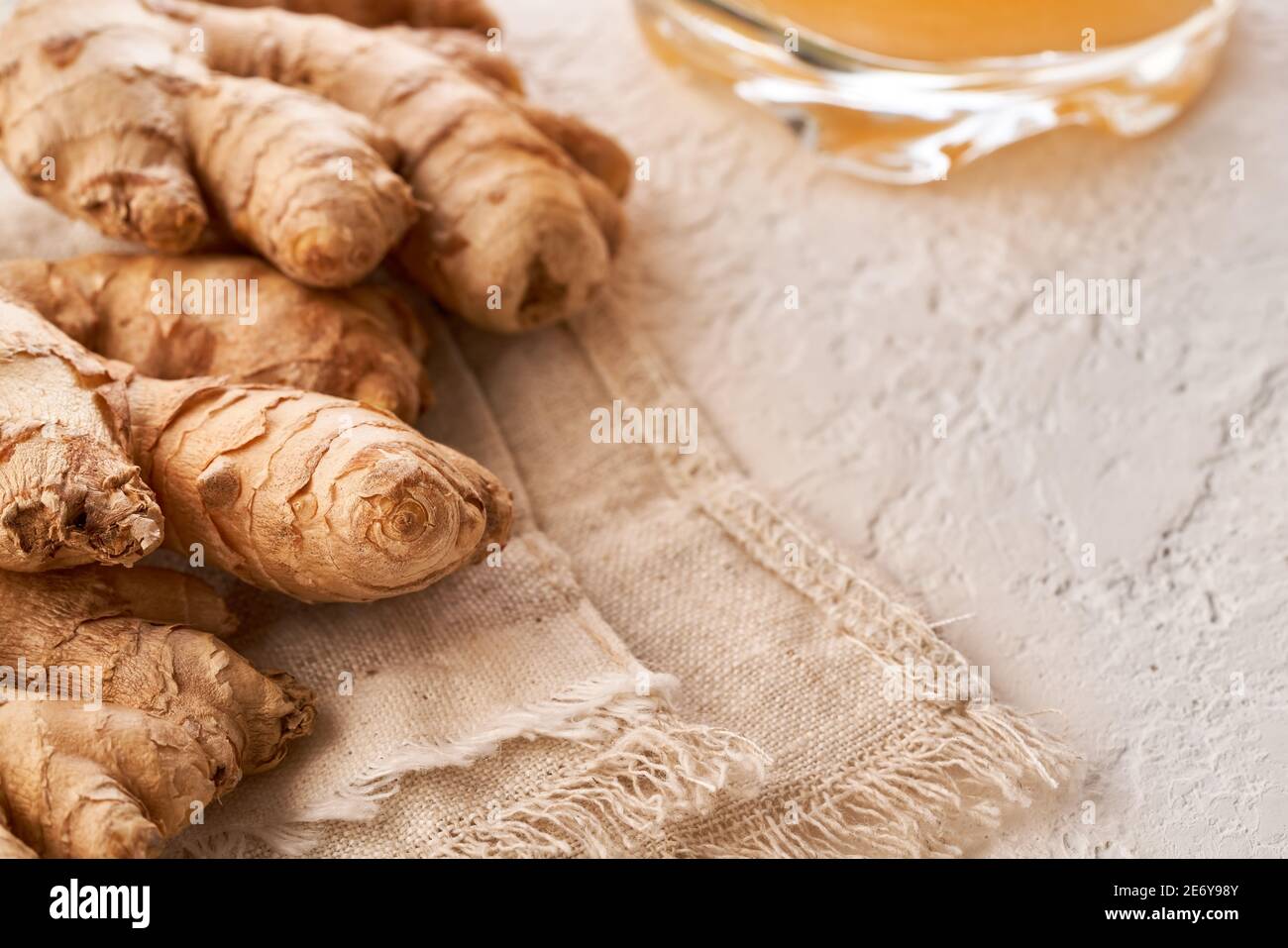 Whole ginger root on a bright table with copy space, with a natual probiotic drink in the background Stock Photo