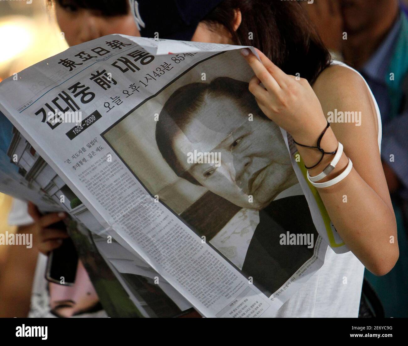 Women read an extra edition of a newspaper reporting on former South Korean President Kim Dae-jung's death at the Seoul railway station August 18, 2009. Former South Korean President Kim, a towering figure in South Korea's struggle for democracy who won the 2000 Nobel Peace Prize for seeking rapprochement with the communist North, died on Tuesday at the age of 85. An official at a Seoul hospital treating Kim for pneumonia confirmed the death.  REUTERS/Jo Yong-Hak (SOUTH KOREA POLITICS OBITUARY) Stock Photo