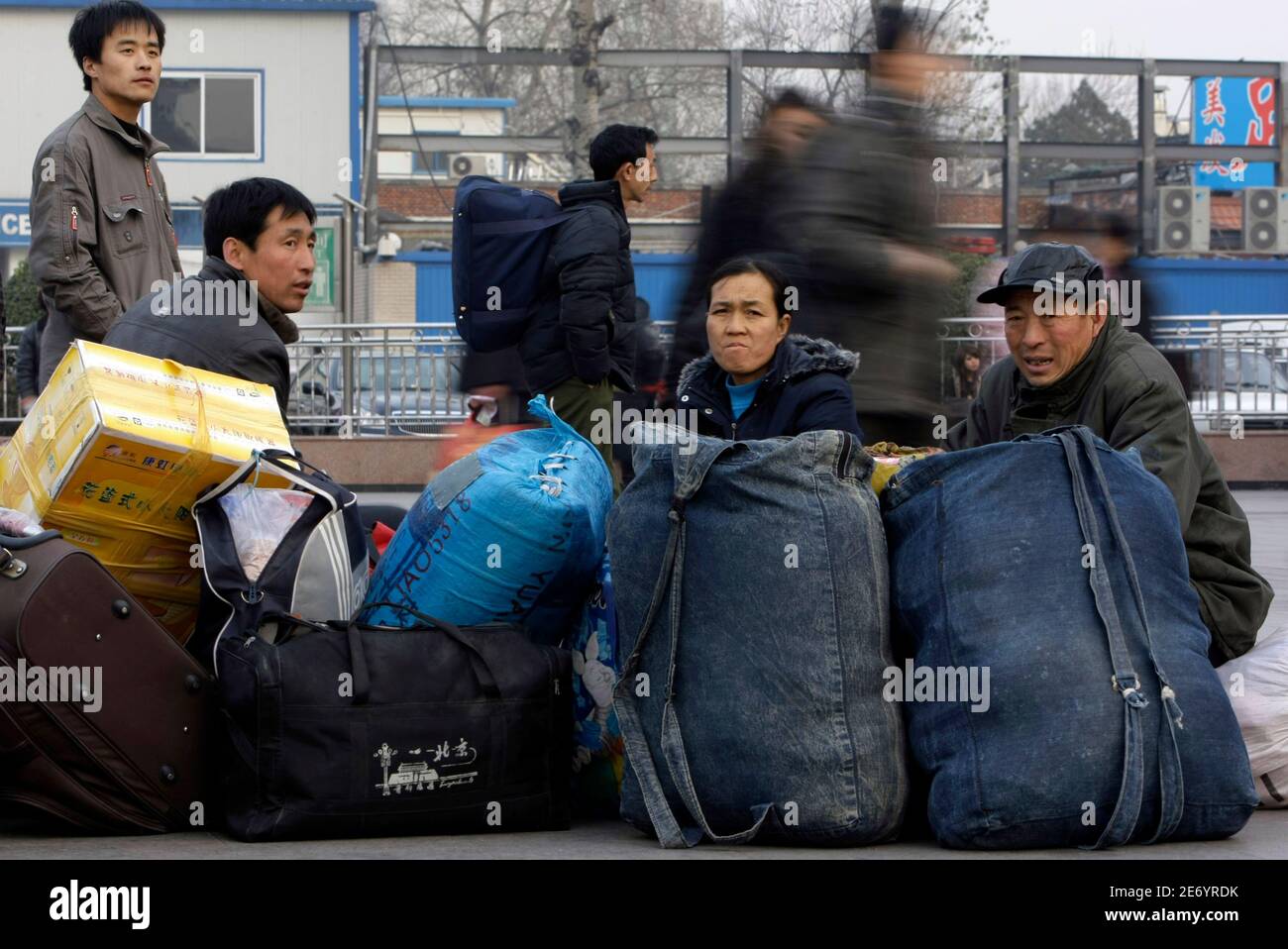 Migrant workers sit next to their baggage as they wait to go back home at Beijing Railway Station December 9, 2008. China's job market will weaken to a two-year low in the first quarter of 2009 as the global financial crisis takes its toll, Manpower Inc said in a survey released on Tuesday. REUTERS/Jason Lee (CHINA) Stock Photo