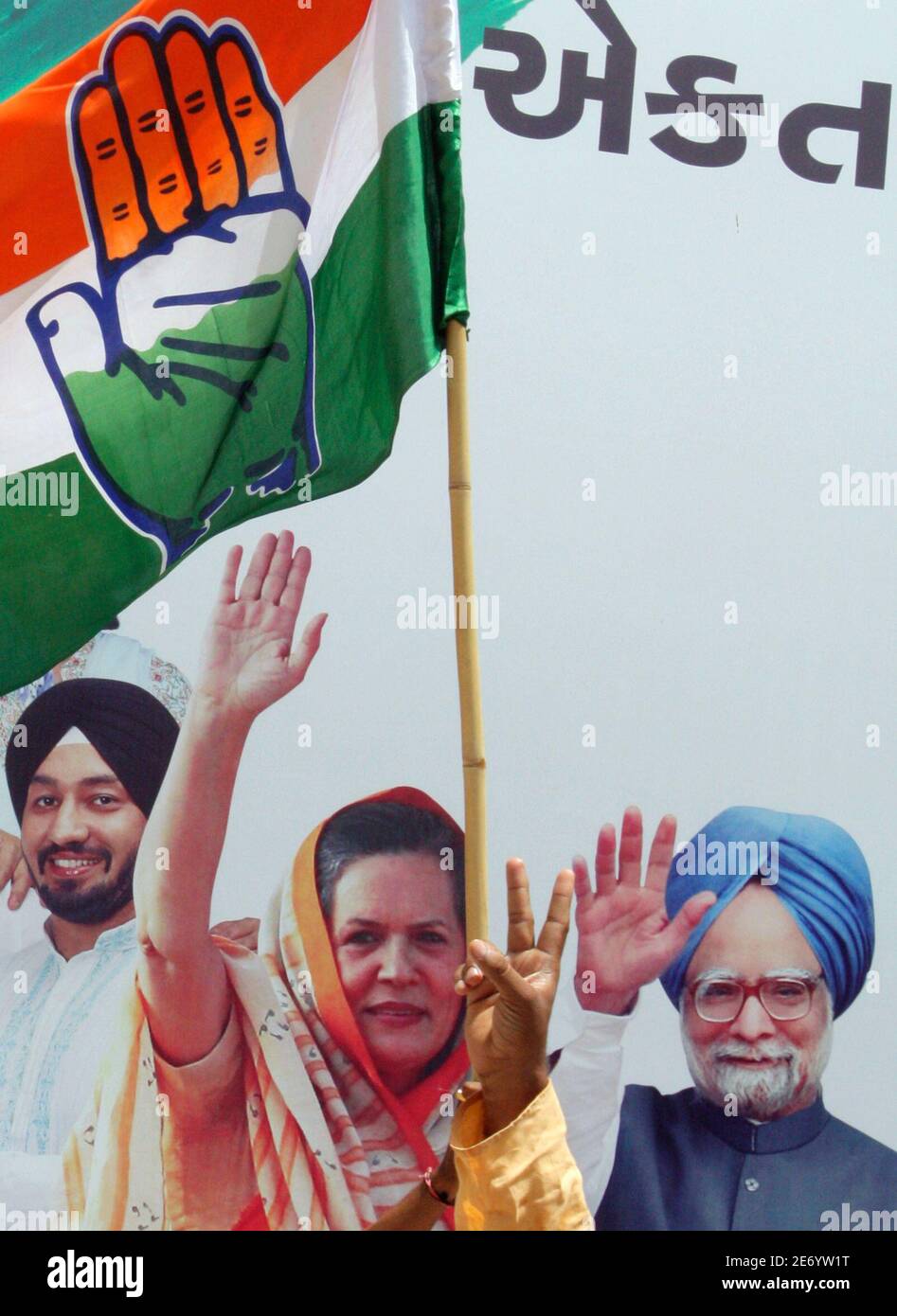 A supporter of the Congress party shows a victory sign in front of a  billboard displaying pictures of Congress chief Sonia Gandhi and Prime  Minister Manmohan Singh (R) outside the party's office
