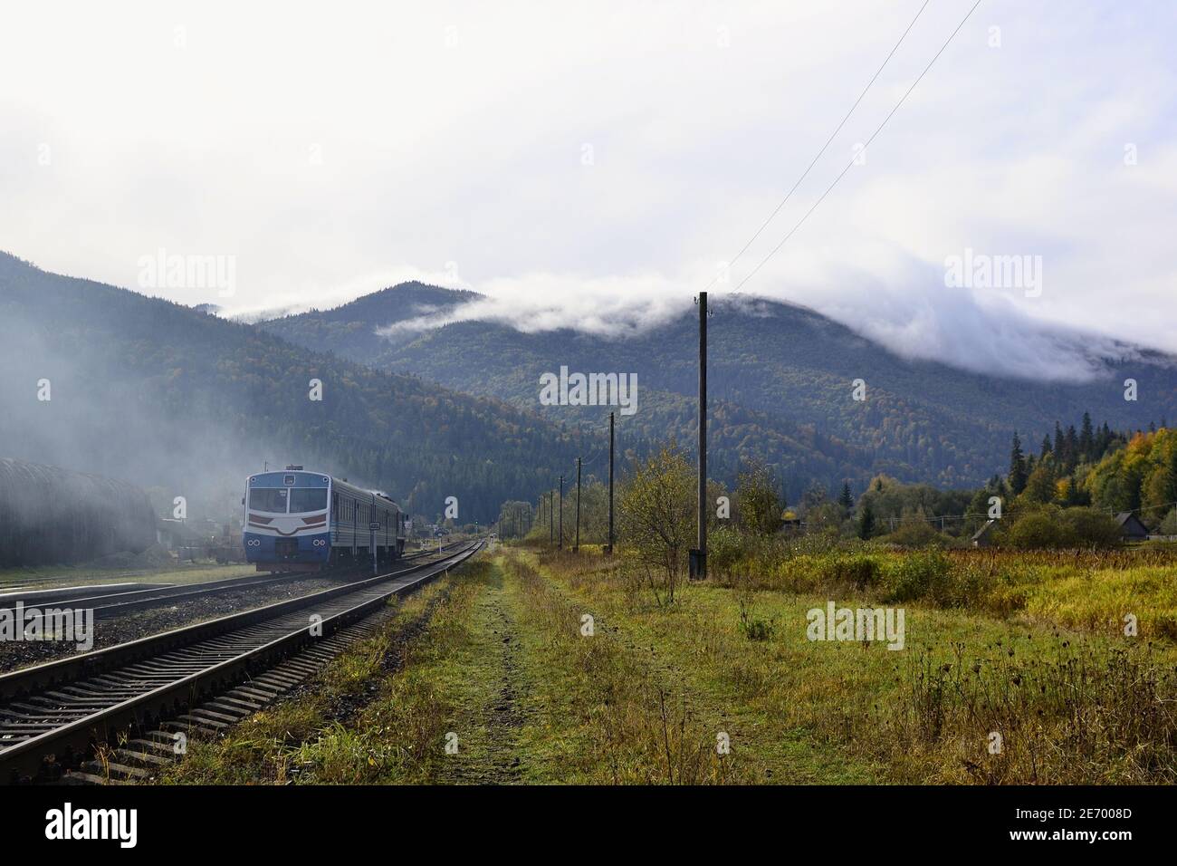 Diesel train on the mountain railway and stunning view of mountain range in the clouds