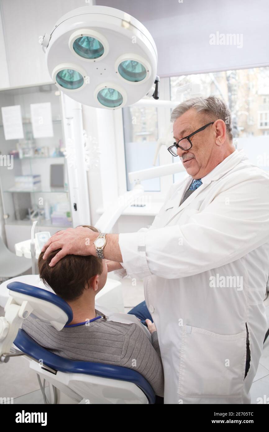 Vertical shot of a senior doctor examining lymphatic nods of a patient before dental treatment Stock Photo