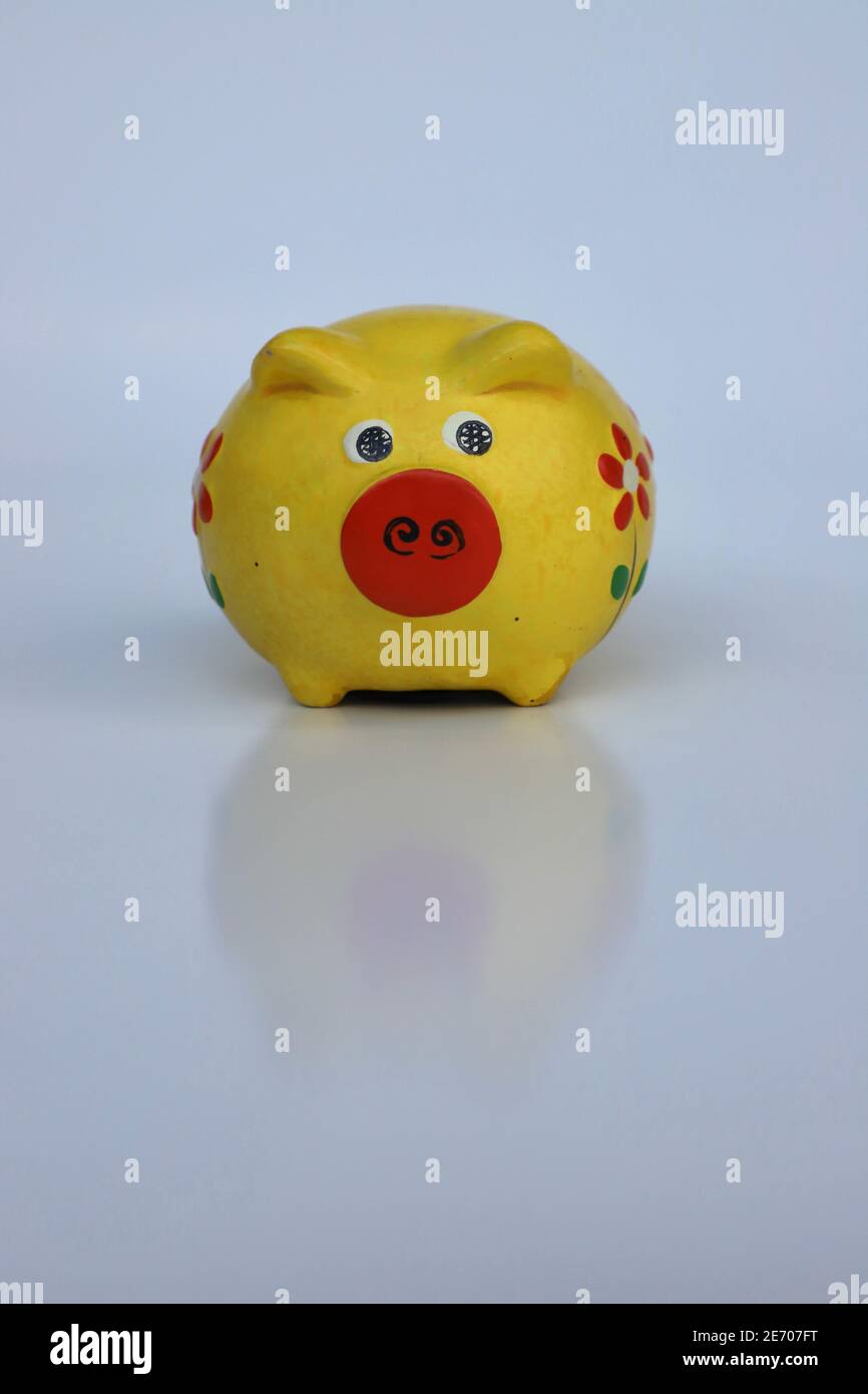 Yellow piggy bank with reflection against a white background with copy space Stock Photo