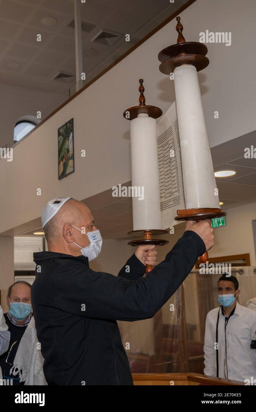 Jerusalem, Israel - January 28th, 2020: A man wearing a protective mask, raising a torah scroll , in a Jerusalem synagogue. Stock Photo