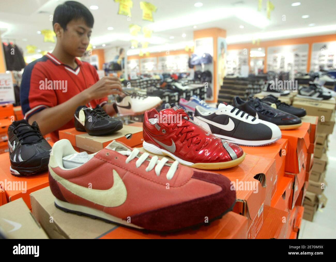 A worker holds a Nike shoe at a shopping mall in Jakarta July 17, 2007.  Sportswear giant Nike Inc. intends to expand its use of Indonesia as a  production hub, despite a