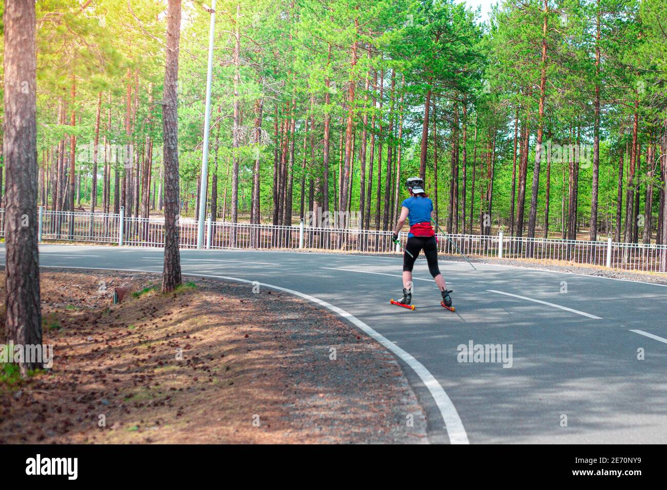 woman athlete is rolling down the track on roller skis, healthy lifestyle, summer skiing training Stock Photo