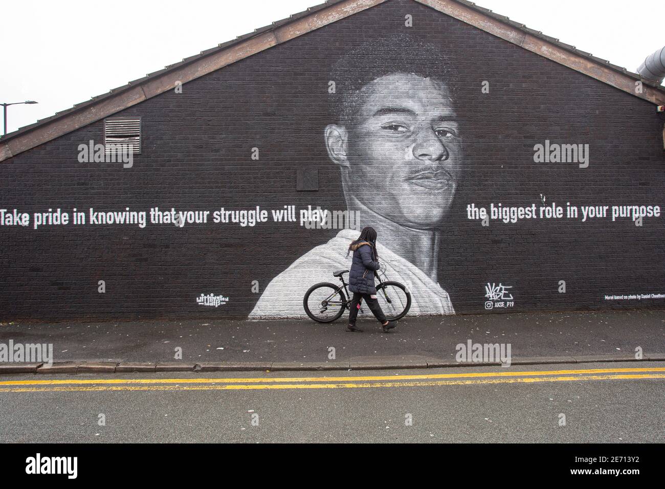 Black child is passing the mural of Manchester United football player Marcus Rashford on the side of a building in Withington, Manchester, northwest E Stock Photo