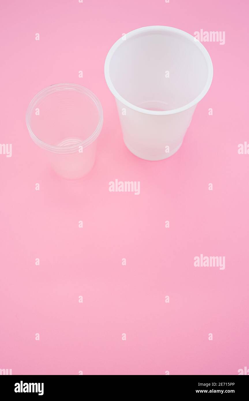 Vertical shot of big and small plastic cups on a pink surface Stock ...