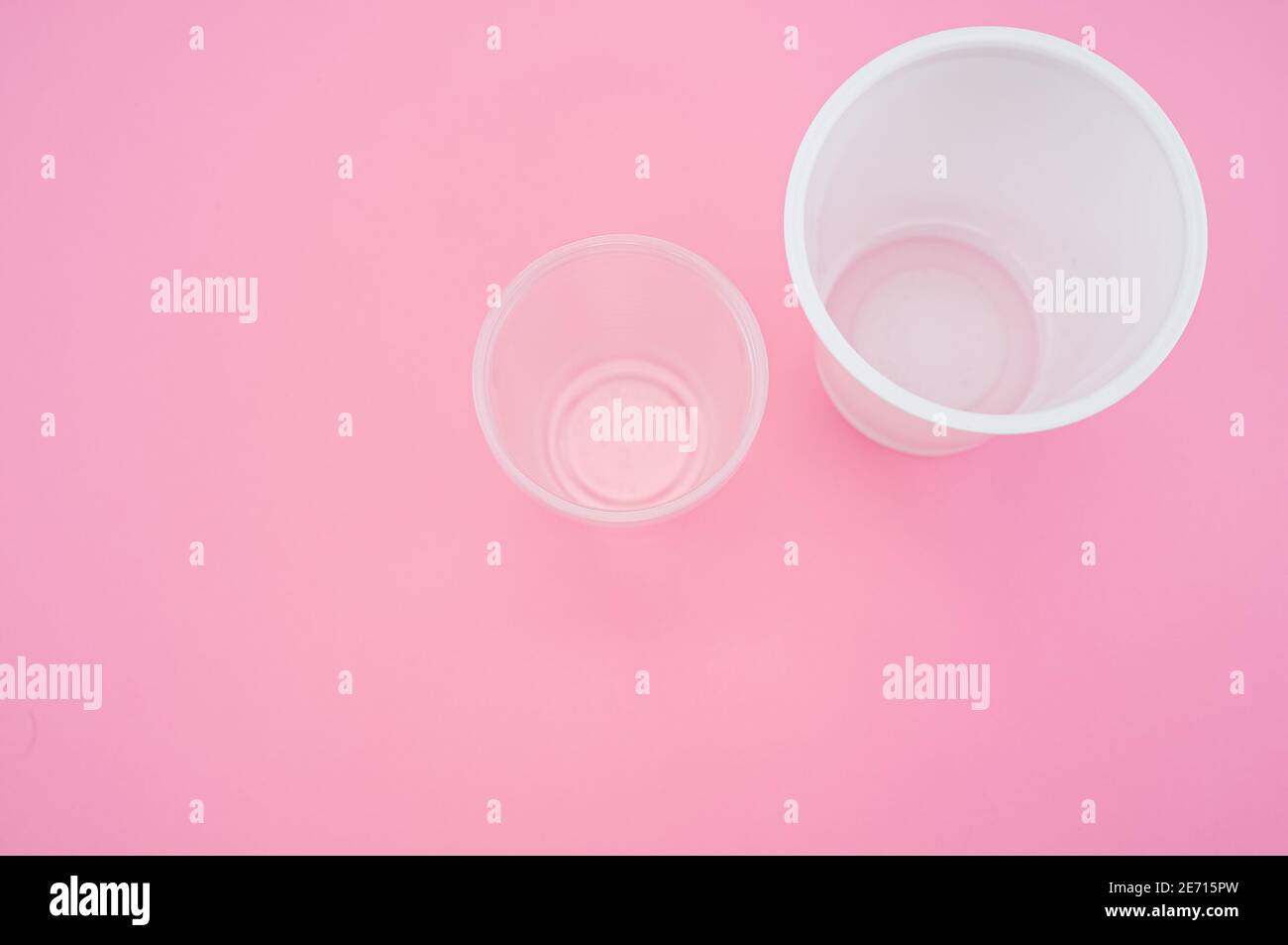 High angle shot of big and small plastic cups on a pink surface Stock ...
