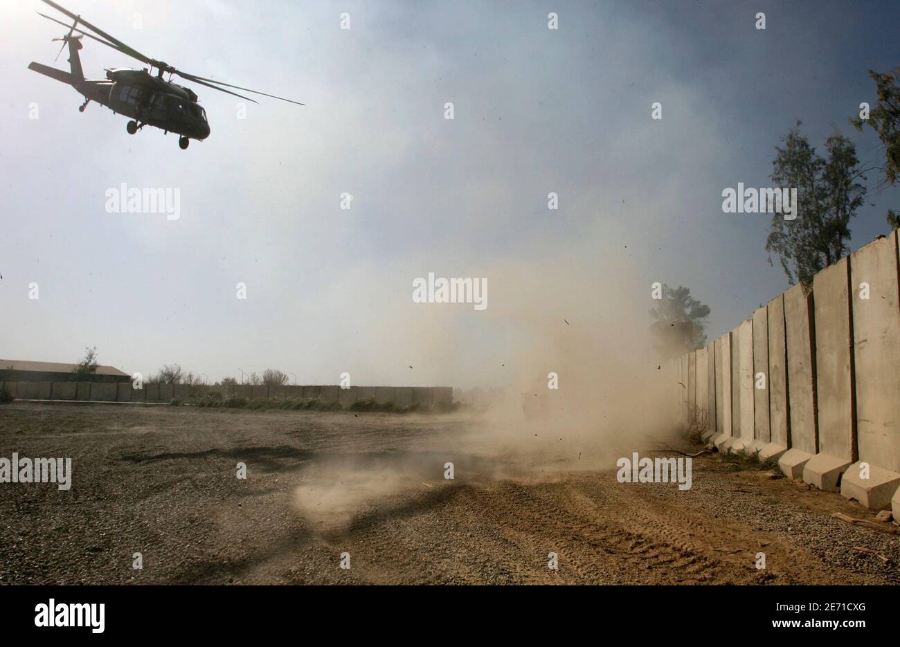 A U.S. tank (covered with smoke and dust) fires towards insurgents to give cover to a U.S helicopter flying out of Combat Outpost Cahill, a small U.S. military camp southeast of Baghdad, November 6, 2007. It's a typical confrontation in the Iraq war -- insurgents with low-tech weaponry emerging from hiding to launch pinprick attacks, and then trying to slip back into the shadows before the U.S. military can hit back with vastly superior firepower. To match feature IRAQ/LYNCH   REUTERS/Erik de Castro  (IRAQ) Stock Photo