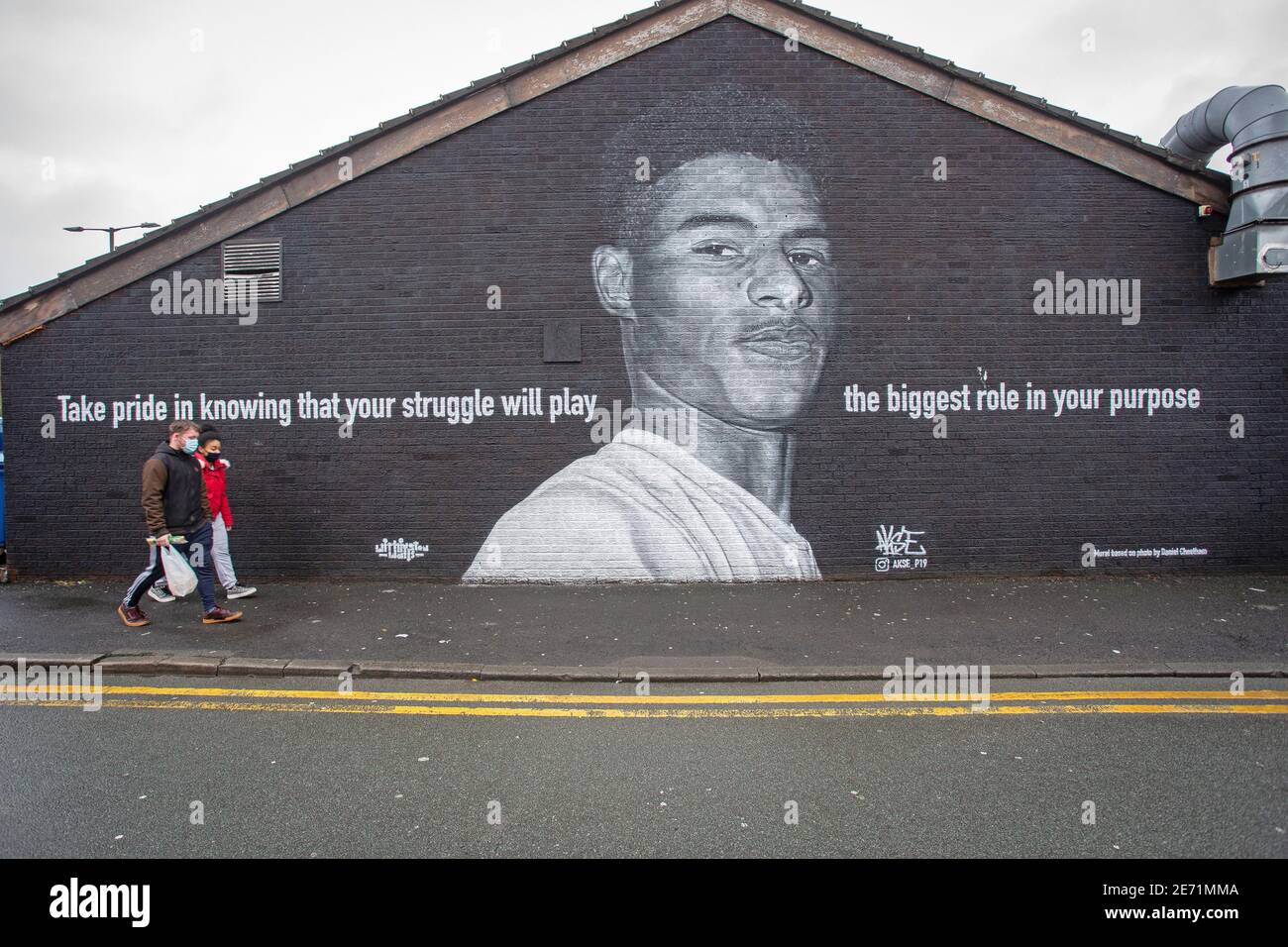 Pedestrians  passing the mural of Manchester United football player Marcus Rashford on the side of a building in Withington, Manchester. Stock Photo