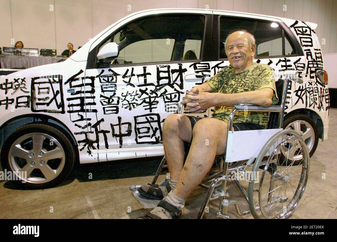 Hong Kong's graffiti king Tsang Tsou-choi poses with a Daihatsu car he decorated with his calligraphy during the 'Japan@Cool Expo' show in Hong Kong in this August 22, 2002 file photo. Tsang died on July 15, 2007 due to sickness in a hospital at the age of 86, his fashion designer friend William Tang told reporters on July 25, 2007. Tsang, also known as 'Kowloon Emperor', is dismissed by many people as just another old grubby loony, but his calligraphy graffiti have won international recognition as art, including sales at Sotheby's. For over four decades, he has been writing Chinese characters Stock Photo