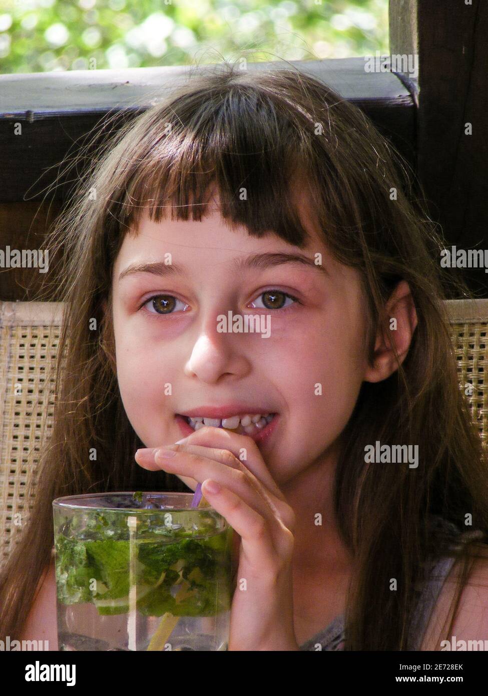 Portrait of happy little girl drinking orange juice water with lemon ...