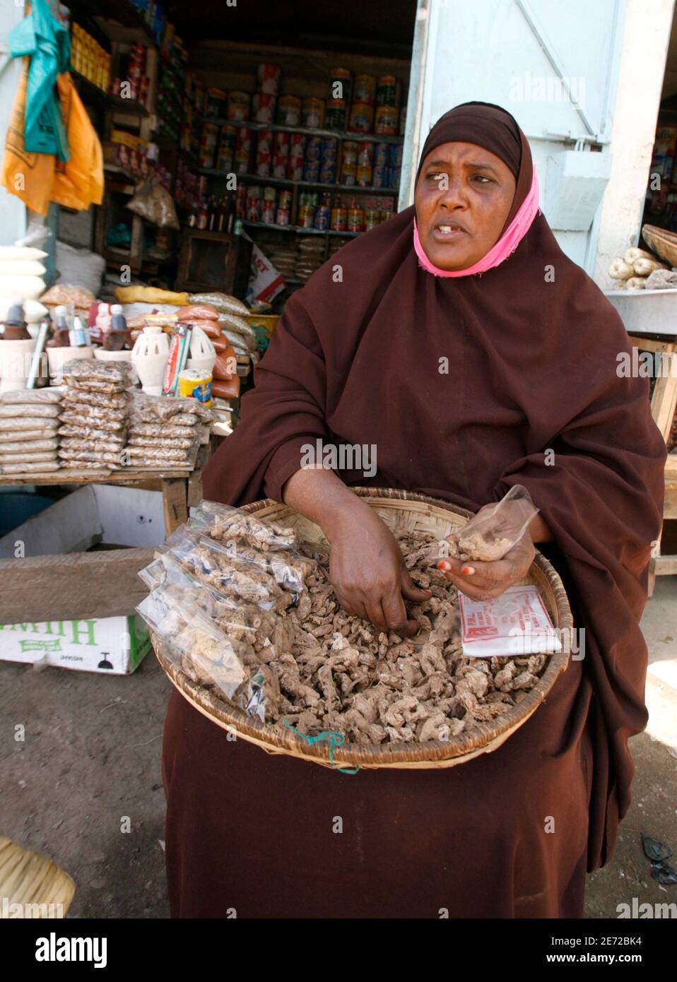 A Somali woman packs ginger roots in bags in the Eastleigh neighbourhood of Nairobi, June 25, 2009. The bustling Eastleigh suburb has been the hub of business for Kenyan-Somalis and thousands of refugees escaping civil war in neighbouring Somalia for decades. But as people flee the continuing conflict in Somalia, the population is outgrowing Eastleigh's 'Little Mogadishu' and Somalis are venturing into other parts of the city. Picture taken June 25, 2009. REUTERS/Thomas Mukoya (KENYA SOCIETY CONFLICT BUSINESS) Stock Photo