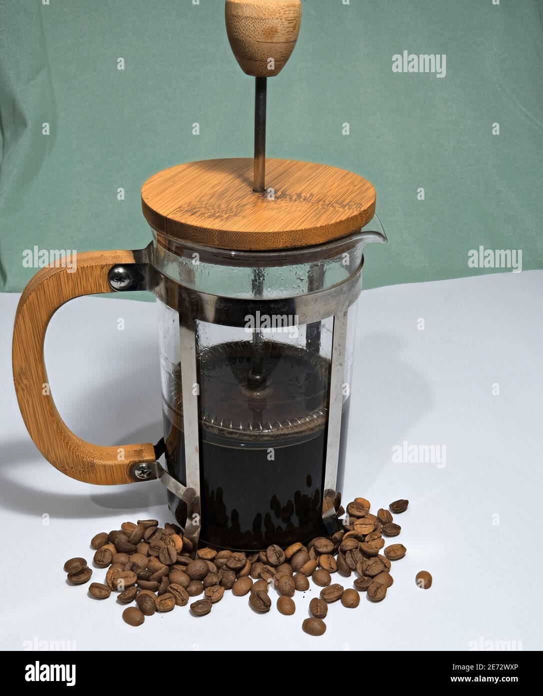 Arabic coffee beans bottom of the french press and cooked caffe inside the  glass side of the press and wooded details with dull green background Stock  Photo - Alamy