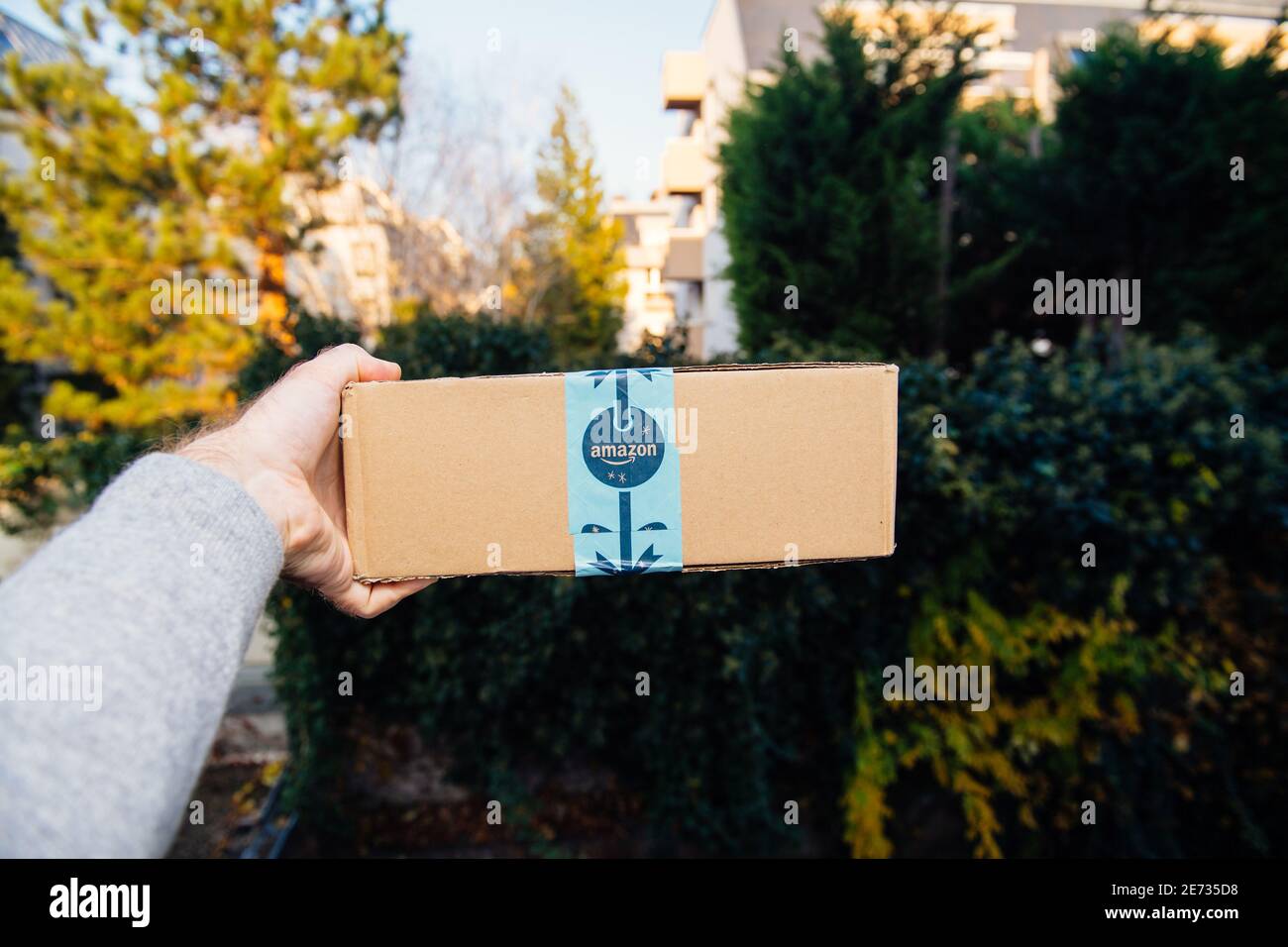Paris, France - Nov 16, 2018: POV personal perspective male hand holding showing Amazon Prime cardboard with festive holiday scotch tape - defocused city background Stock Photo