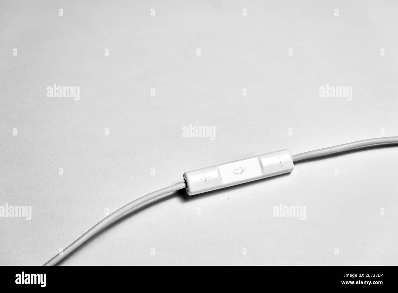 White earpiece controller for volume increasing and decreasing with isolated white background and its white electric cable. Stock Photo
