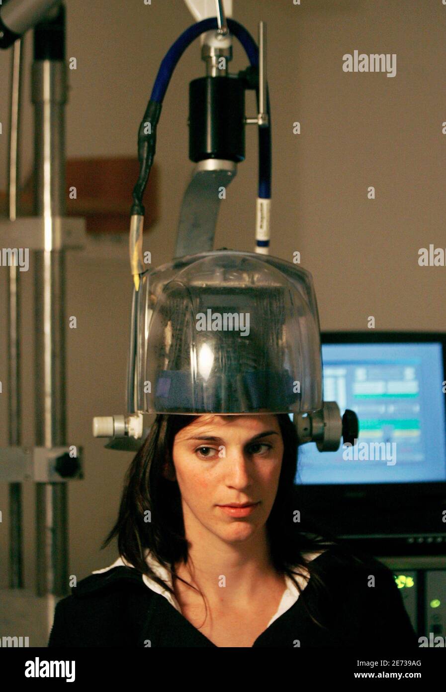 A hospital worker sits under a wired helmet while demonstrating an  experimental treatment for clinical depression at Shalvata Mental Health  Care Centre in the central Israeli town of Hod Hasharon December 4,