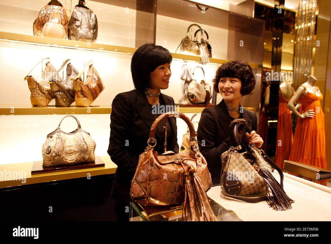 Staff members of the new Gucci flagship store in Shanghai chat as they wait  for customers on its opening day June 6, 2009. Luxury brand Gucci plans to  open two to four