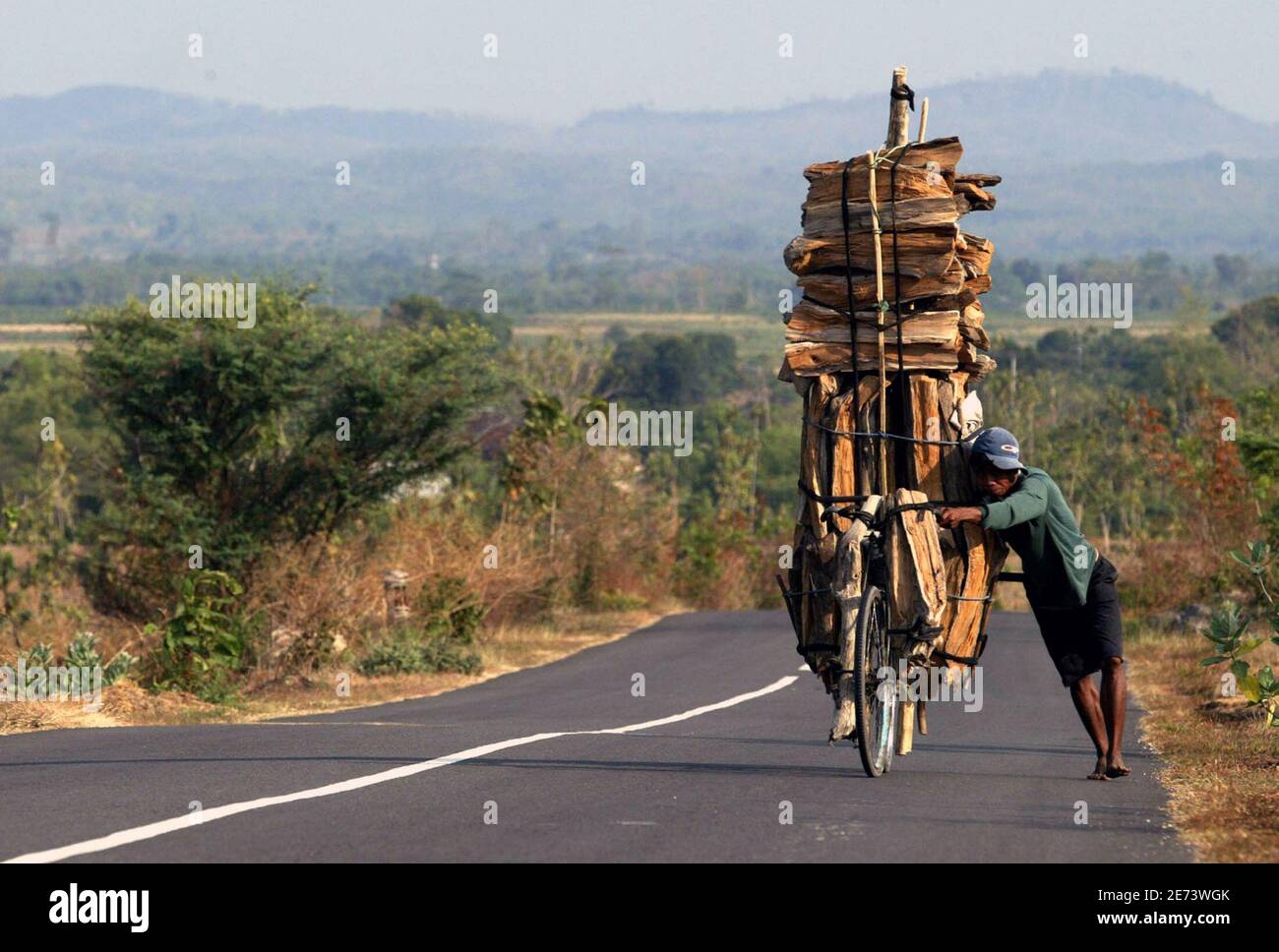 An Indonesian Man Pushes A Bicycle Laden With Fire Wood Down A Highway 40 Km 24 Miles From The Town Bojonegoro East Java September 25 05 The Man Will Use The 25 000 Rupiah