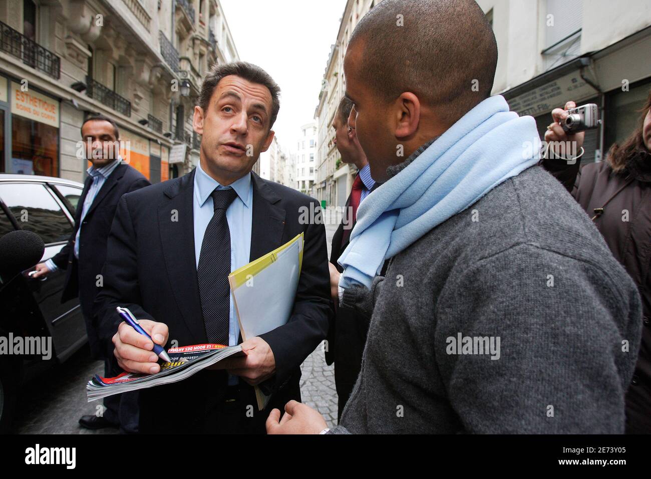 UMP's Presidential candidate Nicolas Sarkozy signs an autograph on the  cover of 'Le Point' where he is represented along with Francois Bayrou, as  he leaves the Skyrock radio station after an interview