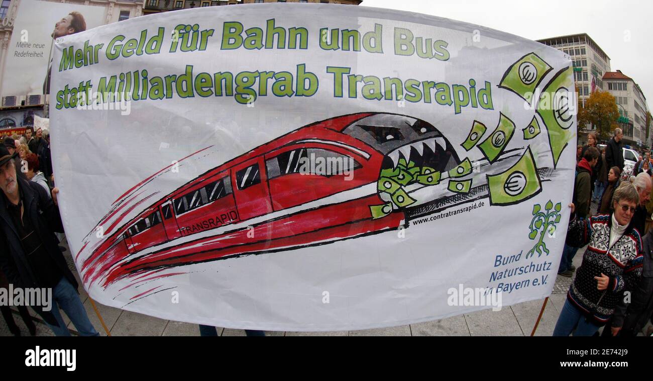 Protesters hold a placard reading "More money for railway and bus instead  of a grave for billions of euros Transrapid" while they and about 13.000  protesters take part at a demonstration against