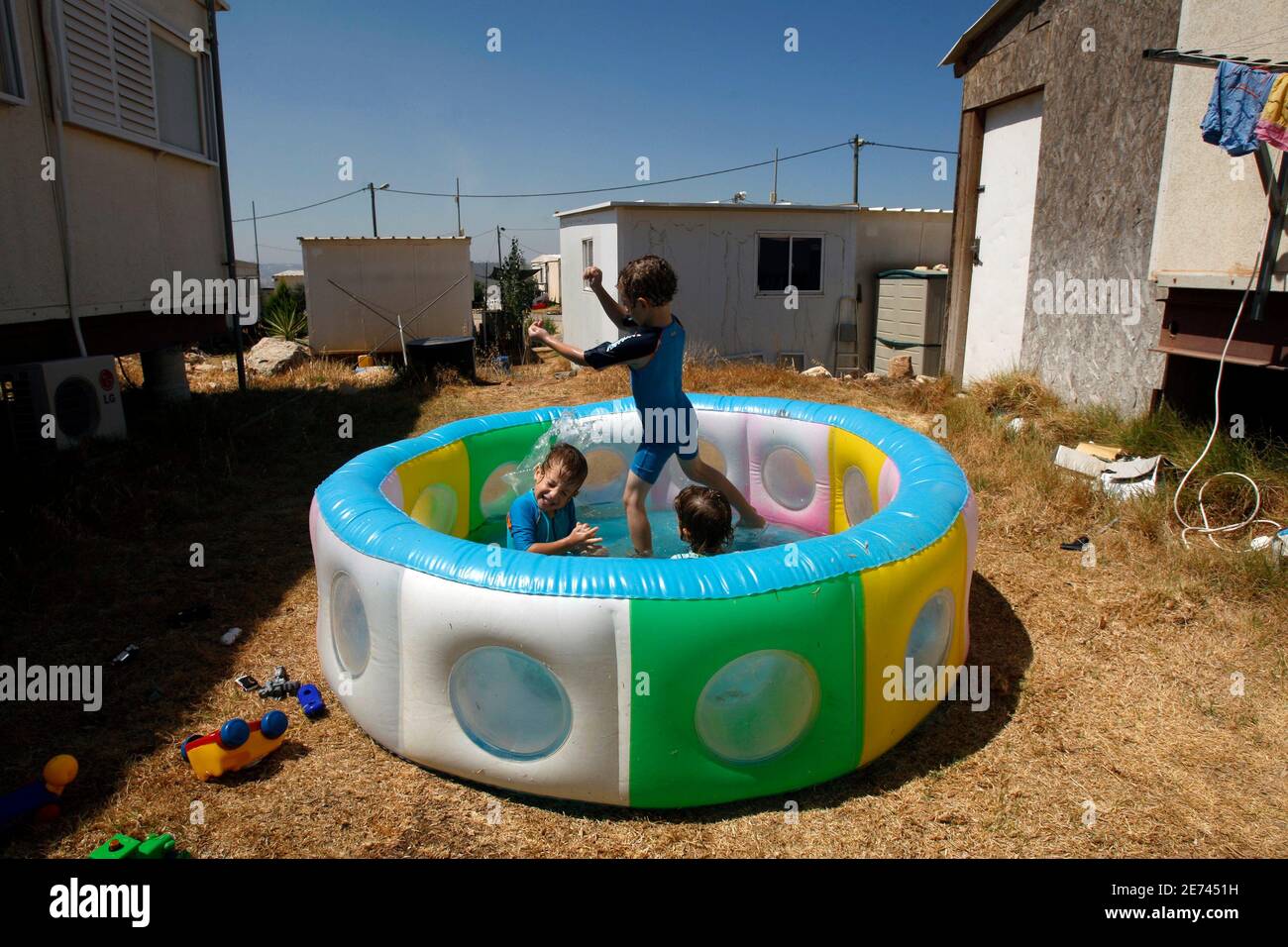 Jewish settler children play in an inflatable pool at the Migron outpost near the West Bank city of Ramallah August 12, 2008. Israel will expand a Jewish enclave in the occupied West Bank to absorb dozens of settlers listed for eviction from the hilltop outpost, built six years ago without government authorisation, an official said on Tuesday. REUTERS/Baz Ratner (WEST BANK) Stock Photo