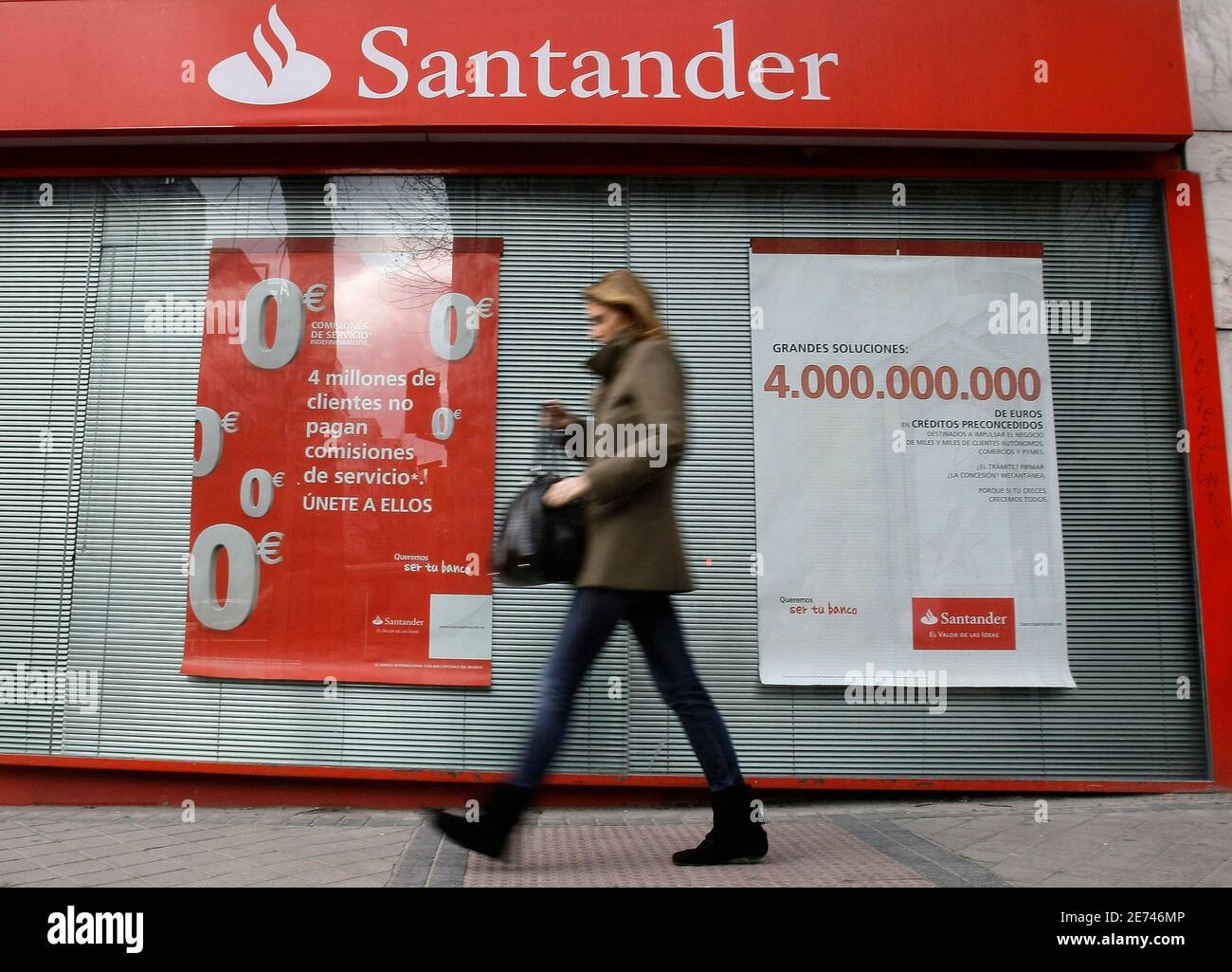 A woman walks past a santander bank branch hires stock photography and