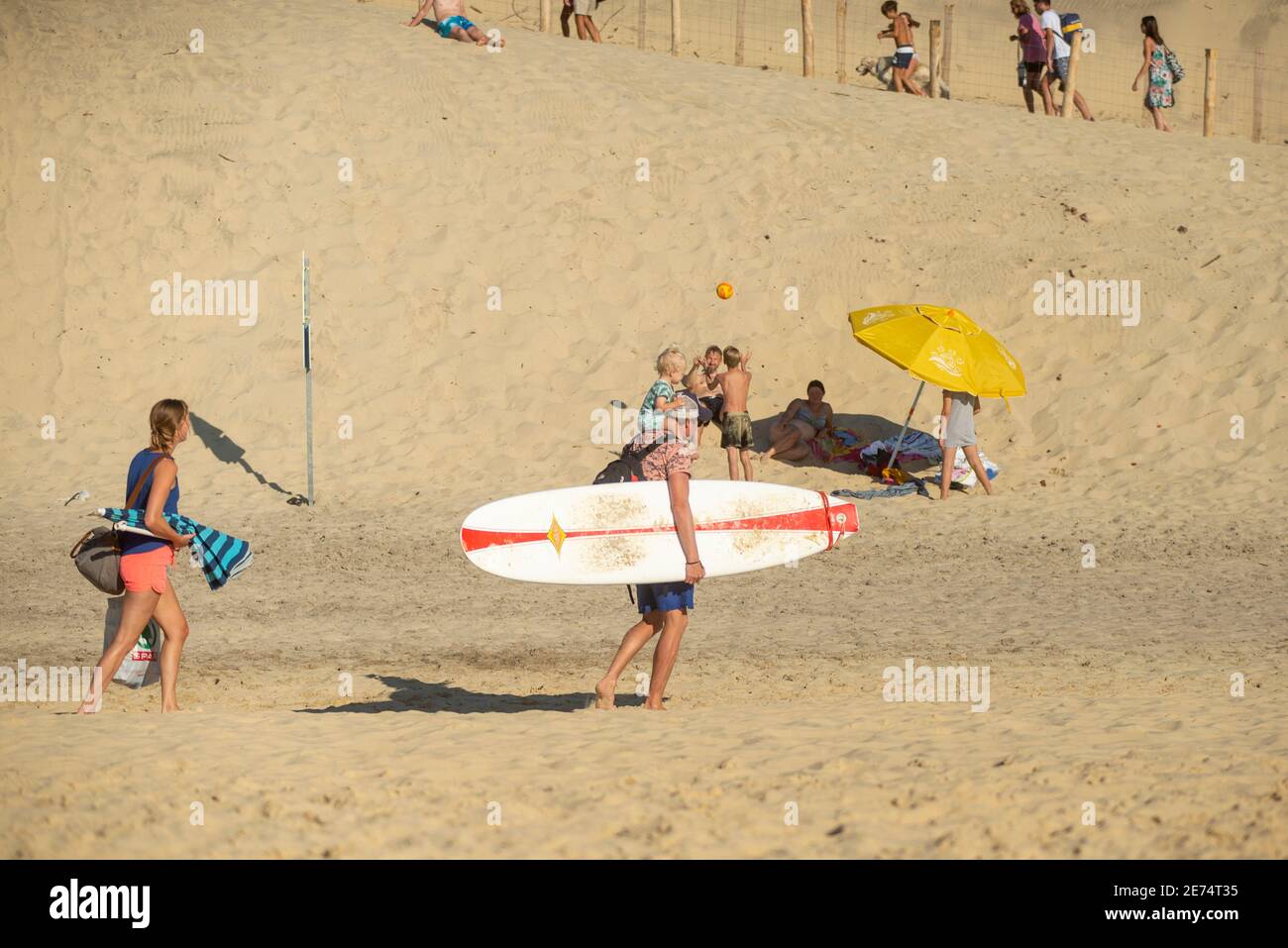 Man with surfboard leaving the beach with his family in Biscarrosse.Biscarrosse Plage is an important surf destination on the Atlantic Ocean in France Stock Photo