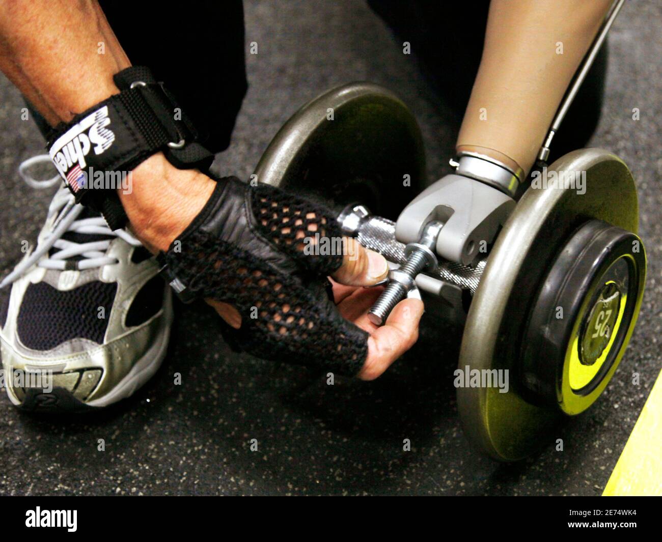 Bob Radocy of TRS Inc. attaches a prosthetic hand designed for weightlifting  to a barbell at a gym in Boulder, Colorado August 21, 2009. Radocy designs  and builds prosthetic attachments that allow