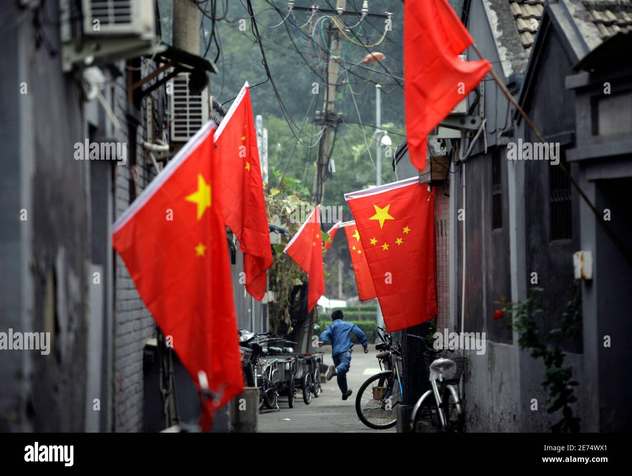 A boy runs along an old Hutong decorated with Chinese national flags to celebrate the upcoming October's 60th anniversary of the founding of the People's Republic of China, in central Beijing September 29, 2009. REUTERS/Jason Lee (CHINA SOCIETY ANNIVERSARY) Stock Photo