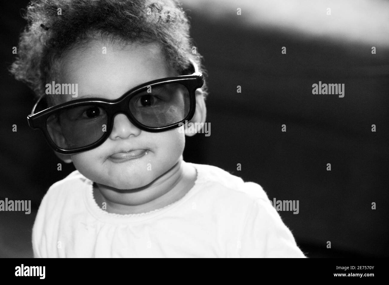 candid black and white portrait of baby wearing over sized glasses Stock Photo