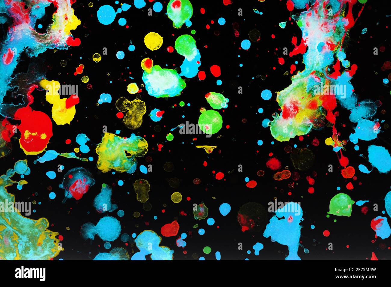 Speckled paint of different colors on a black background Stock Photo