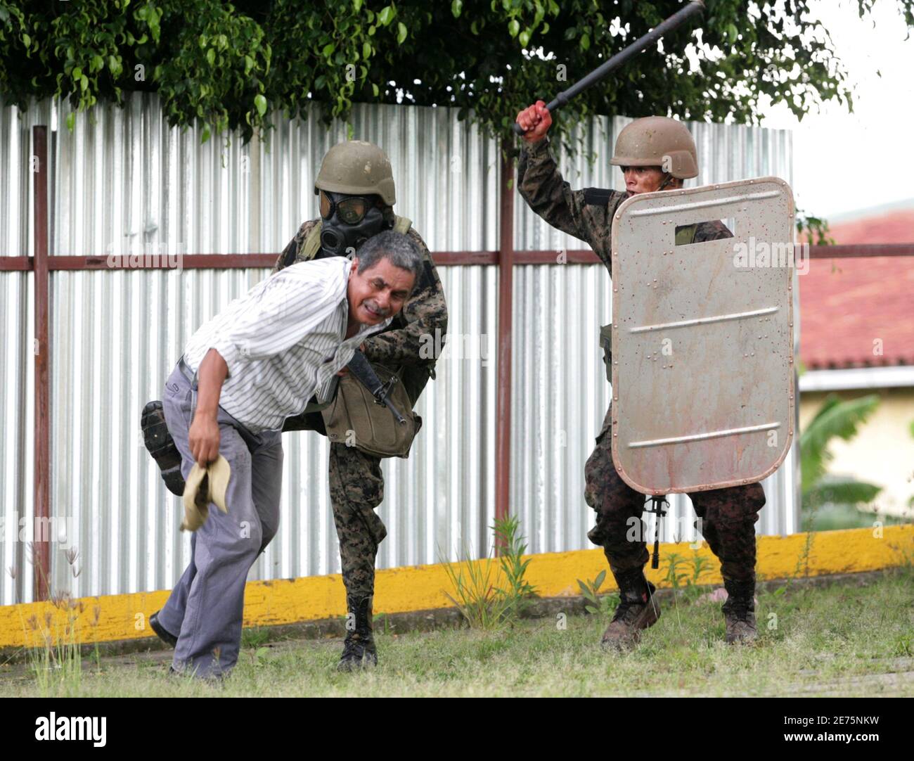 Soldiers attack a supporter of Honduras' ousted President Manuel Zelaya in Tegucigalpa June 29, 2009. Some 1,500 protesters, some of them masked and carrying sticks, taunted soldiers and burned tires just outside the gates of the presidential palace in a face-off with security forces. Honduras came under pressure on Monday to reinstate Zelaya as many Latin American leaders agreed to withdraw envoys. REUTERS/Oswaldo Rivas (HONDURAS POLITICS CONFLICT) Stock Photo