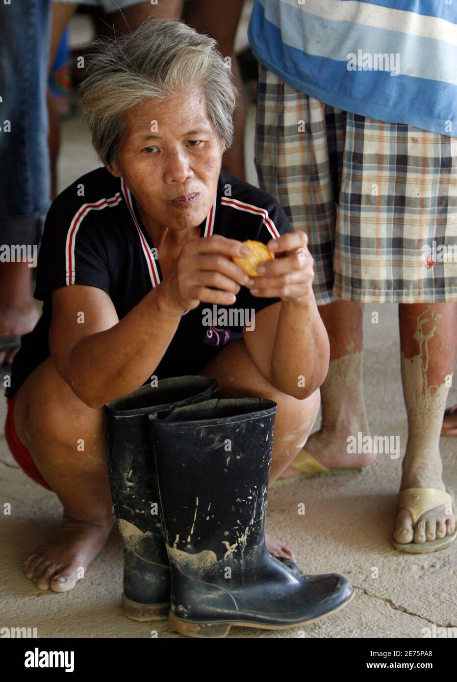 A flood victim eats biscuits while waiting for the distribution of relief supplies from U.S. Marines, 31st Marine Expeditionary Unit in flood-hit town of Rosales, Pangasinan in the northern Philippines October 11, 2009. REUTERS/Erik de Castro    (PHILIPPINES ENVIRONMENT DISASTER) Stock Photo