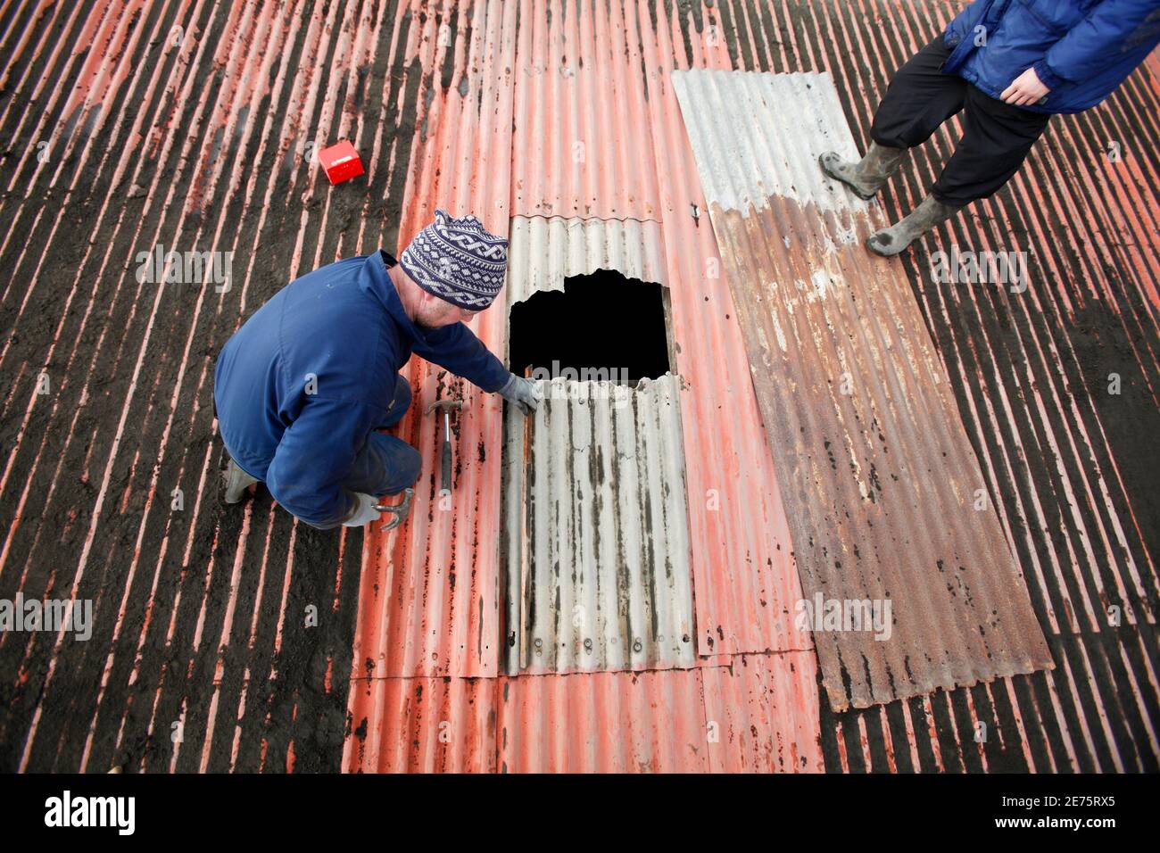 Farmers Bjarni Thorvaldsson and Thorgrimur Bjarnason (R) inspect a hole in a barn roof as they work to clean off volcanic ash that has accumulated from an erupting volcano near Eyjafjallajokull April 18, 2010. REUTERS/Lucas Jackson (ICELAND - Tags: DISASTER ENVIRONMENT) Stock Photo